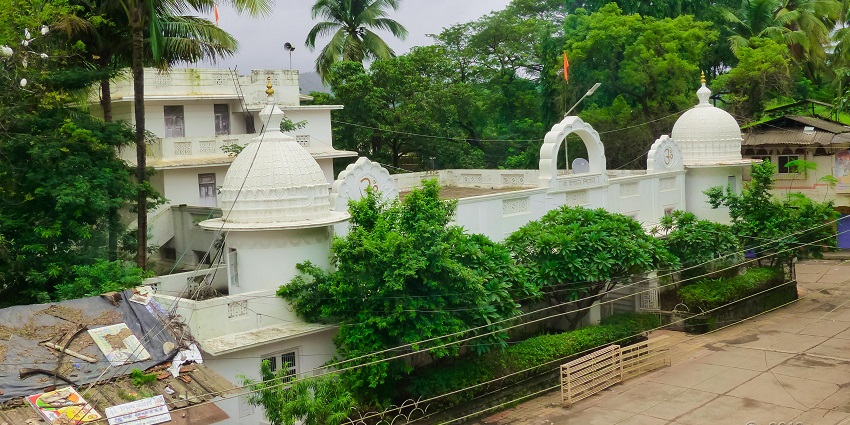 A picture of a temple in a sacred town in Maharashtra surrounded by lush greenery and tall trees
