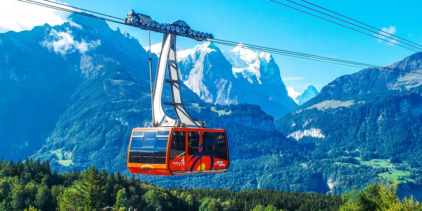 A stunning aerial view of a red cable car against a backdrop of mesmerising mountains.