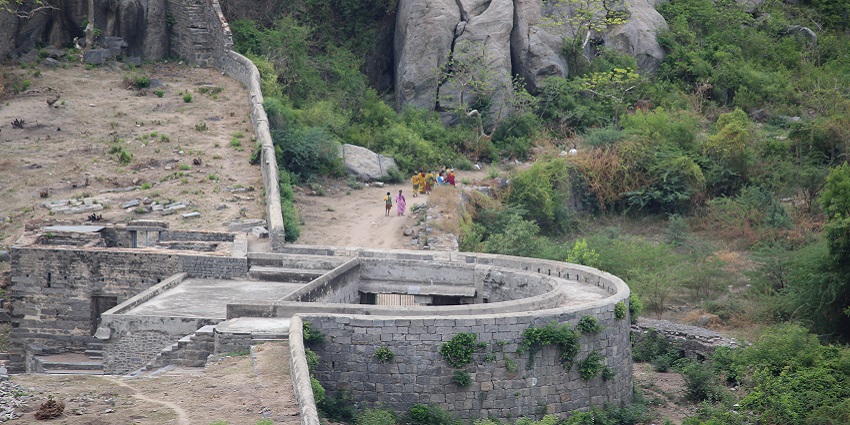 Gingee Fort with stone walls, rocky terrain, and greenery with people walking around