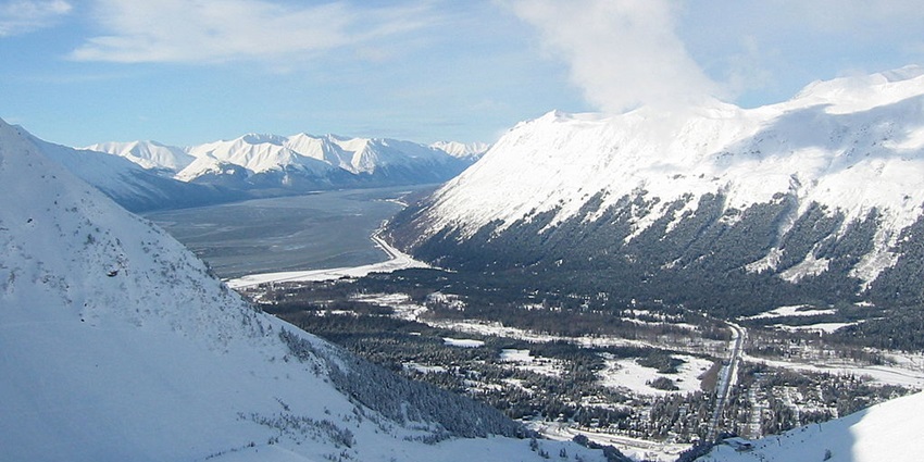 Girdwood valley encompassed by snow-capped mountains and some visible greenery