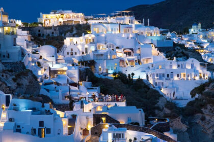 Santorini island at night with well-lit buildings and people enjoying the restaurant