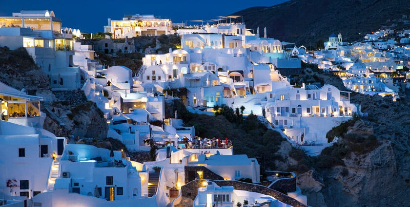 Santorini island at night with well-lit buildings and people enjoying the restaurant