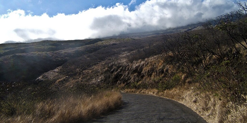 Haleakā National Park with mountains covered by clouds and dried grass and plants
