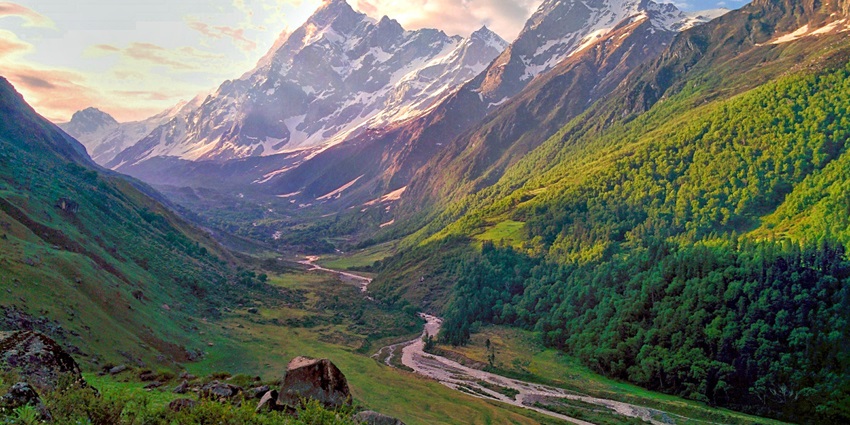 Har Ki Dun valley with lush meadows, flowing river, and snow-capped Himalayan peaks.