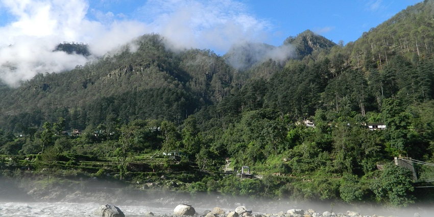 A picture of a mountain with a river flowing in front of it, taken on a clear day