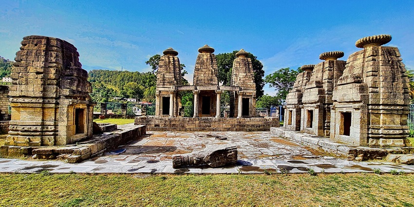 View of Madhyamaheshwar Temple in broad daylight, surrounded by green fields.