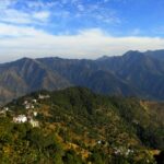 A glimpse of towering mountains dotted with lush green vegetation in Uttarakhand.