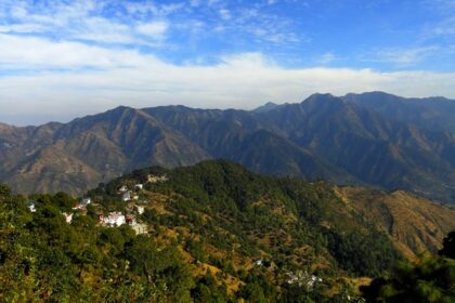 A glimpse of towering mountains dotted with lush green vegetation in Uttarakhand.