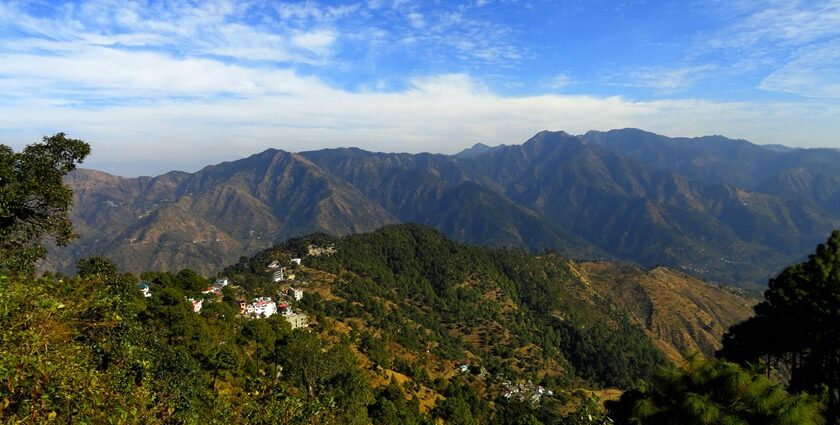 A glimpse of towering mountains dotted with lush green vegetation in Uttarakhand.