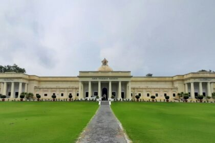 A view of the IIT Roorkee building surrounded by lush greenery grass field under blue sky