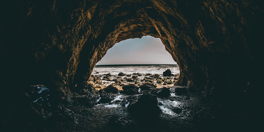 Dramatic sea shore cave with rocky formations and waves crashing