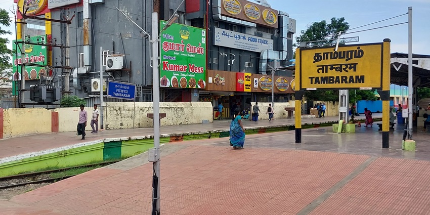 Tambaram Railway Station with multiple platforms, blue roofs, and passengers waiting.