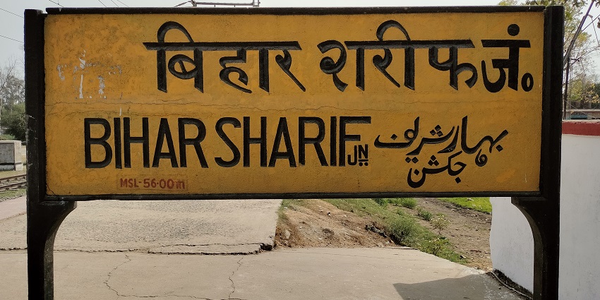 Indian Railways train stopped at Bihar Sharif Junction with a visible board near a dustbin.