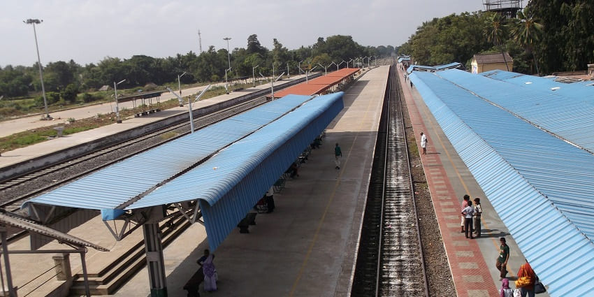 Kumbakonam railway station with platforms, tracks, and people waiting for the train.