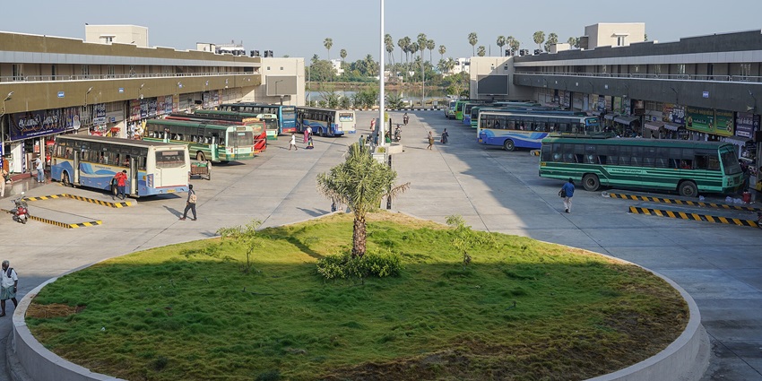 Tirunelveli bus stand with passengers waiting near buses and a landscaped roundabout