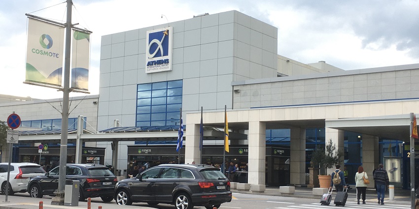 Entrance of Athens International Airport with cars parked and people with their luggage.