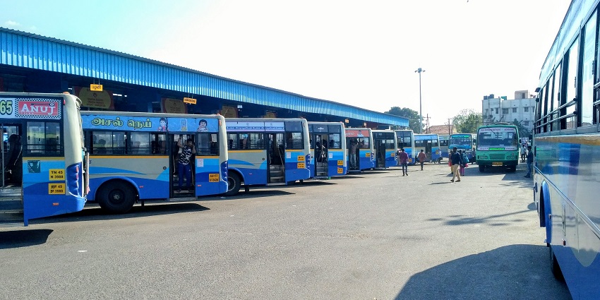 Several buses parked at the Tiruchirappalli central bus stand with fewer people waiting.