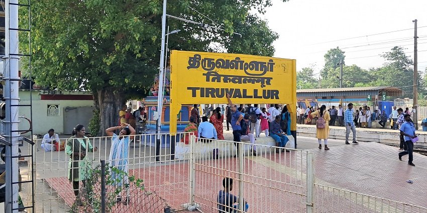 A glimpse of Tiruvallur railway station with a board sign and passengers waiting for the trains.