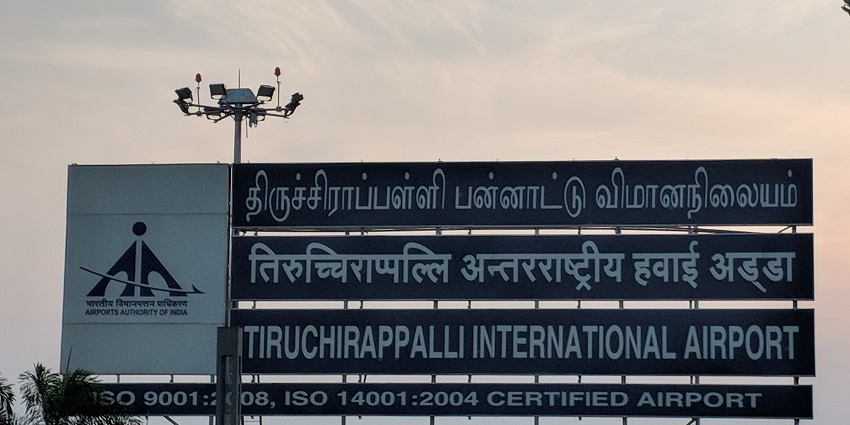A signboard in Tamil and English displaying information about Tiruchirappalli Airport