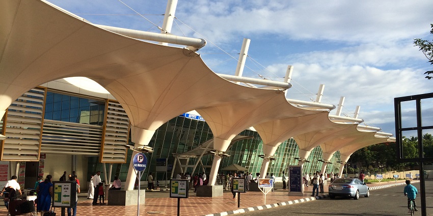 Exterior view of Coimbatore International Airport, featuring the terminal building and parked vehicles.