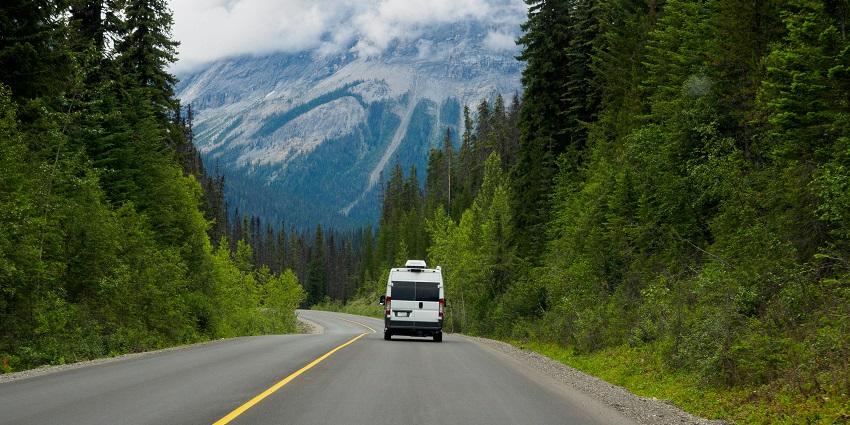 Image of roadways surrounded by lush green mountains and under clear blue sky
