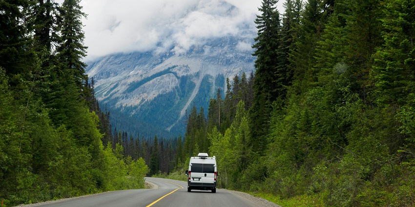 Image of a twisty road surrounded by lush green mountains under clear blue sky