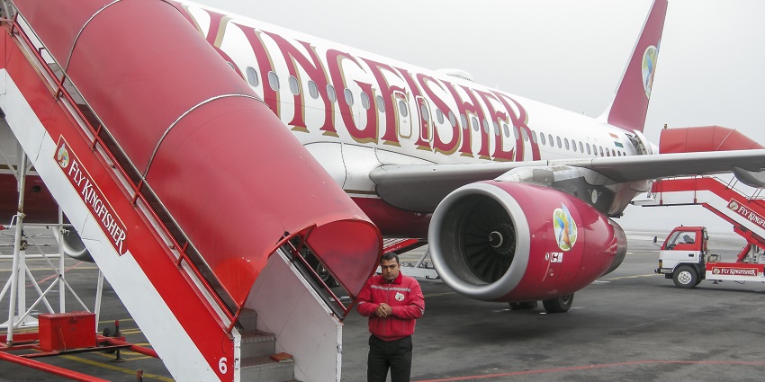 A Fly Kingfisher Airplane on the airport with a mobile staircase and a crew member standing