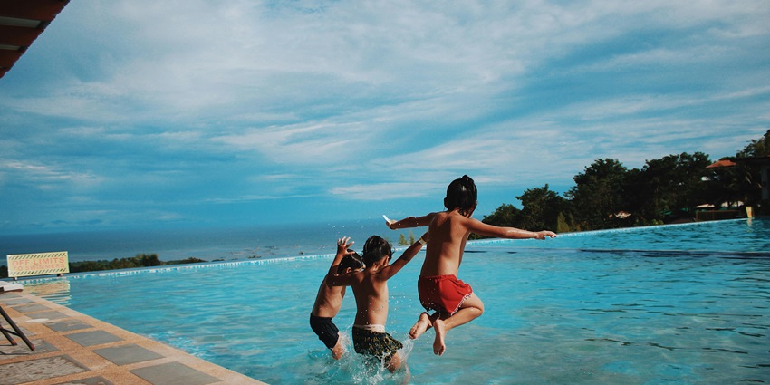 A view of the calm holiday water park with green lawns and surrounding trees.