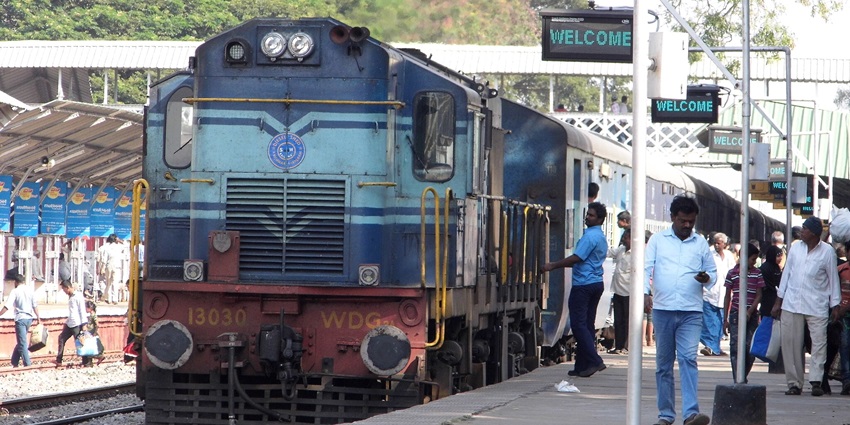 A wide-angle view of a railway station platform with numerous passengers waiting.