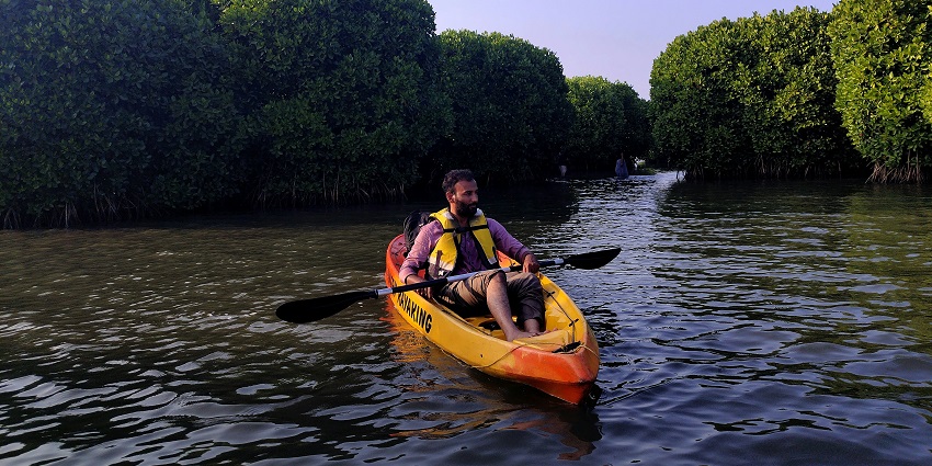 mage of a man kayaking surrounded by lush greenery on both sides