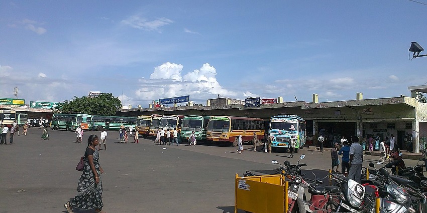 Dindigul Bus Station road with passengers near the parked buses and motorcycles