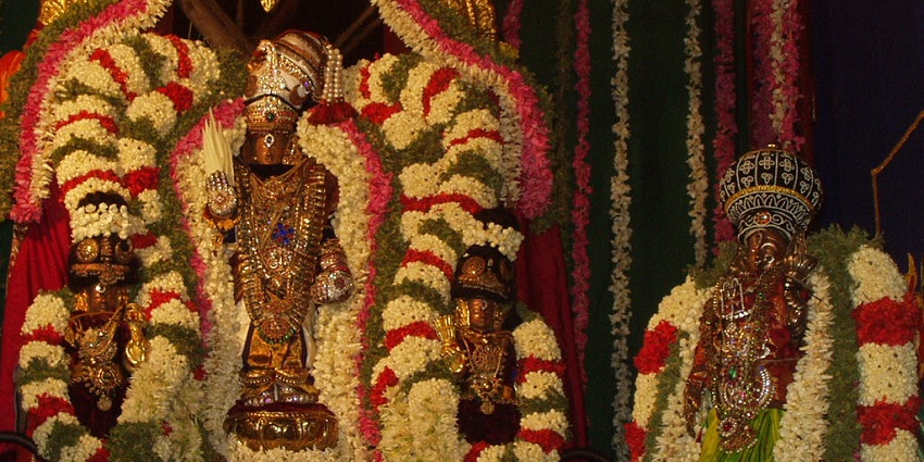An inside view of a temple showcasing flowers alongside Srinivasa Perumal idols.
