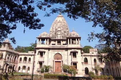 The temple’s entrance with carved pillars, devotees visiting the temple and a streetlight