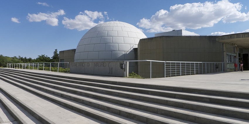 A view of architecture of a planetarium in the city, with wide stairs and blue sky