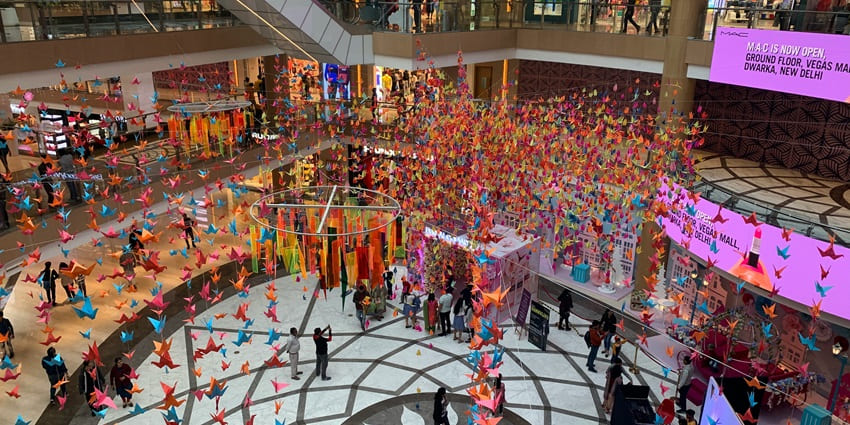A vibrant mall atrium, decorated with hundreds of colourful hanging paper cranes.