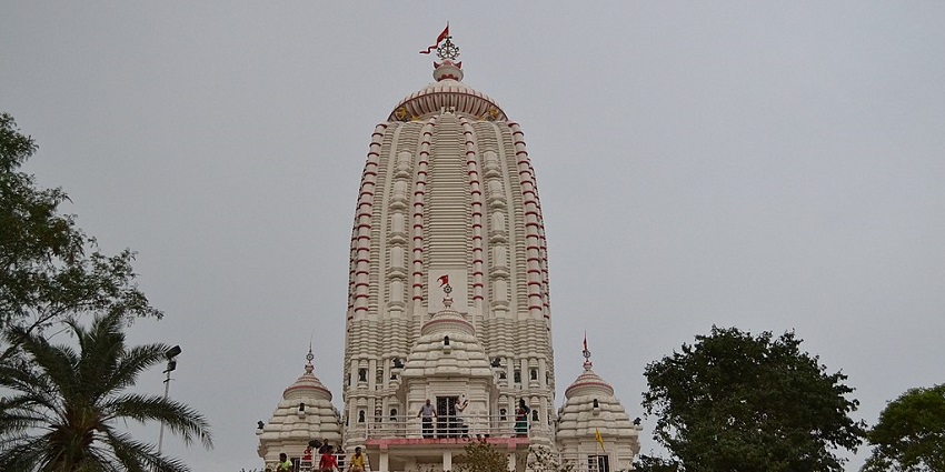 Front view of the Jagannath Mandir, with people in the temple and greenery around.