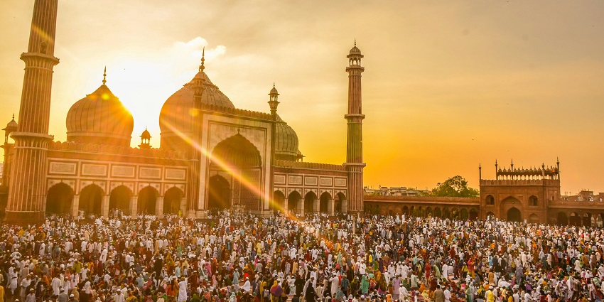 An image showing people gathered before a mosque at golden hour, like in Jama Masjid.