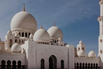 An exterior view of Jama Mosque at sunset, with people gathered in front of it.