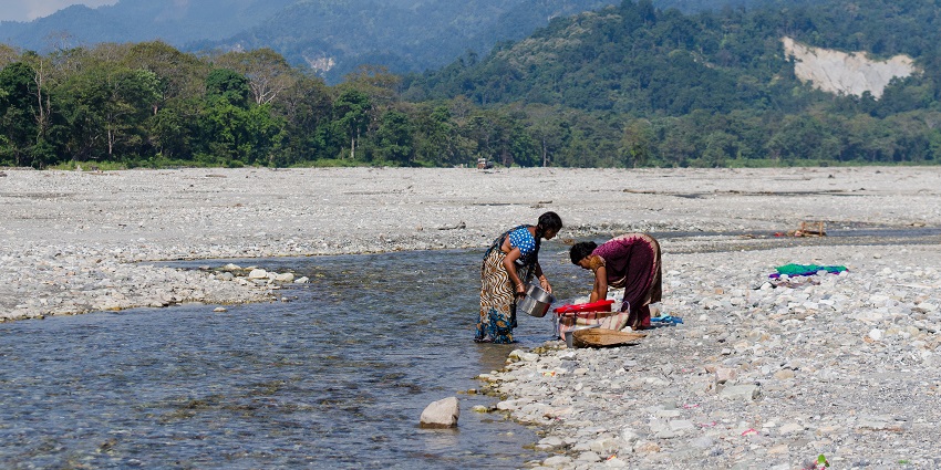 View of the serene Jayanti River, with a mountain range visible in the background
