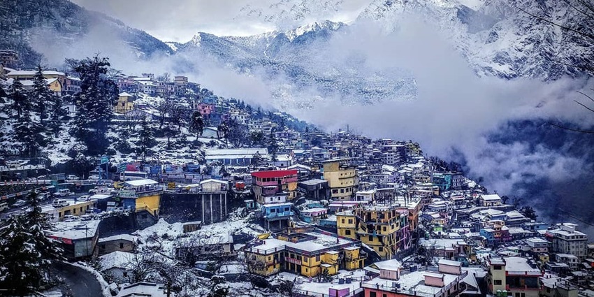 Snow-covered peaks and rooftops in Joshimath, with a serene winter mountain view–hill stations near mukteshwar