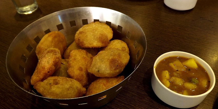 A picture of a delicious north Indian dish made with deep-fried flour, served with potato curry
