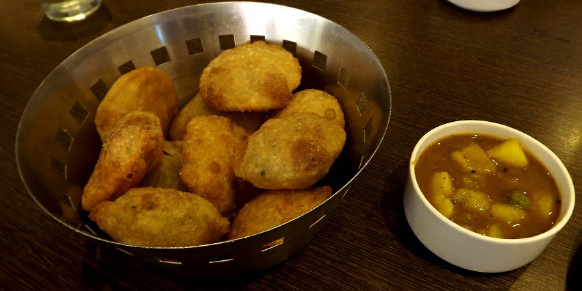 A picture of a delicious north Indian dish made with deep-fried flour, served with potato curry