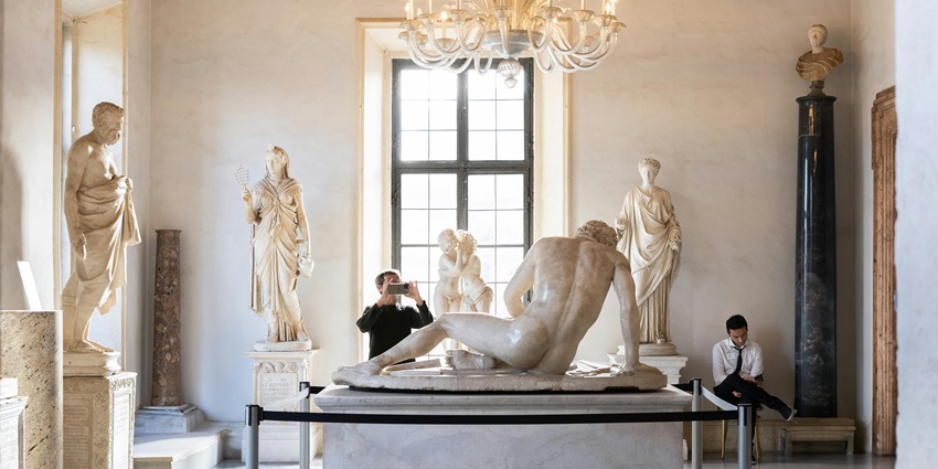A picture of an art admirer looking at a sculpture and studying its details at an art gallery
