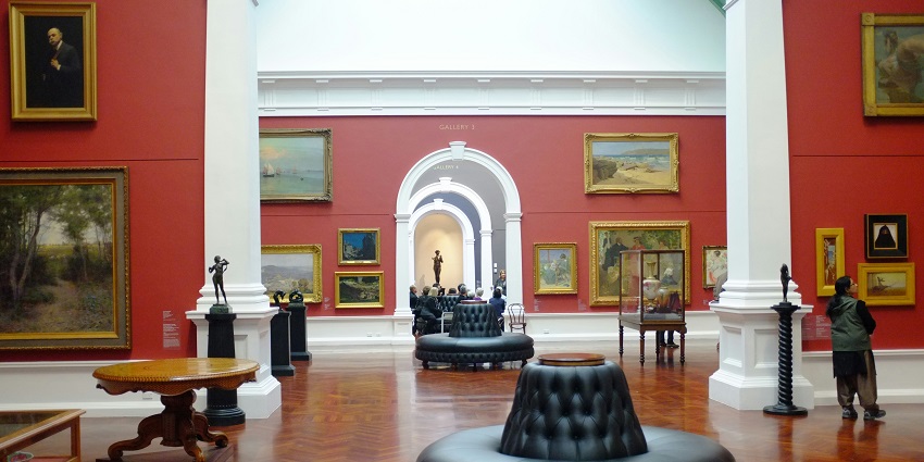 A brightly lit art gallery interior showcasing colourful abstract paintings