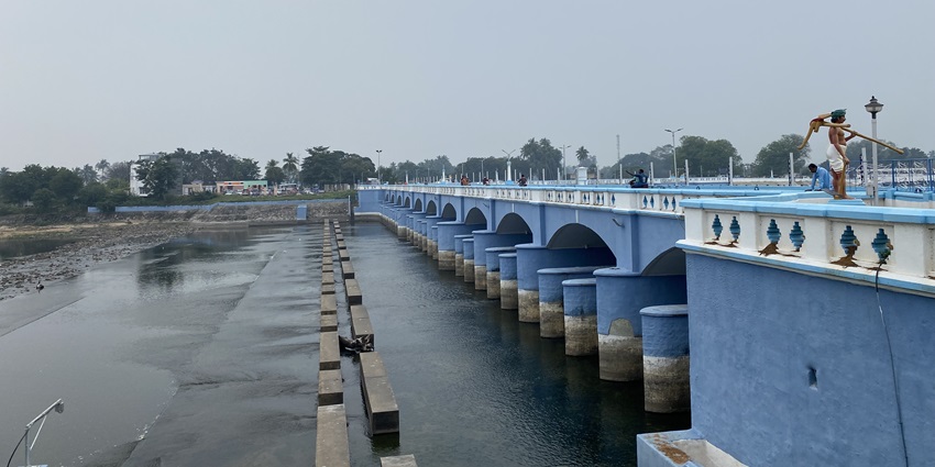 Kallanai Dam’s ancient stone structure over the river with landscapes surrounding it.
