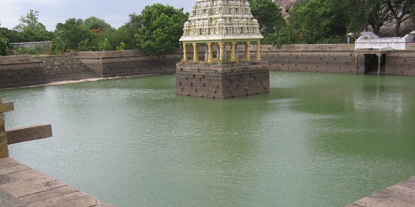 A picture of a quaint pond in a temple complex with a small structure in the middle