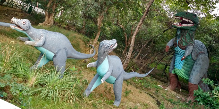 Life-size dinosaur sculptures at Kanpur Zoo, displayed in a natural outdoor setting
