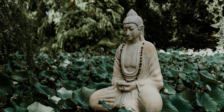 Serene Buddha statue exuding peace, set against a lush natural backdrop.