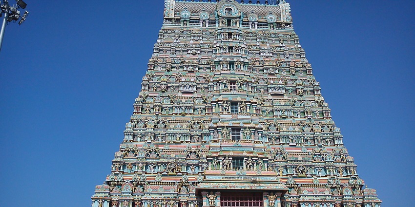 A magnificent temple with intricate carvings is coloured vibrantly on the outside.