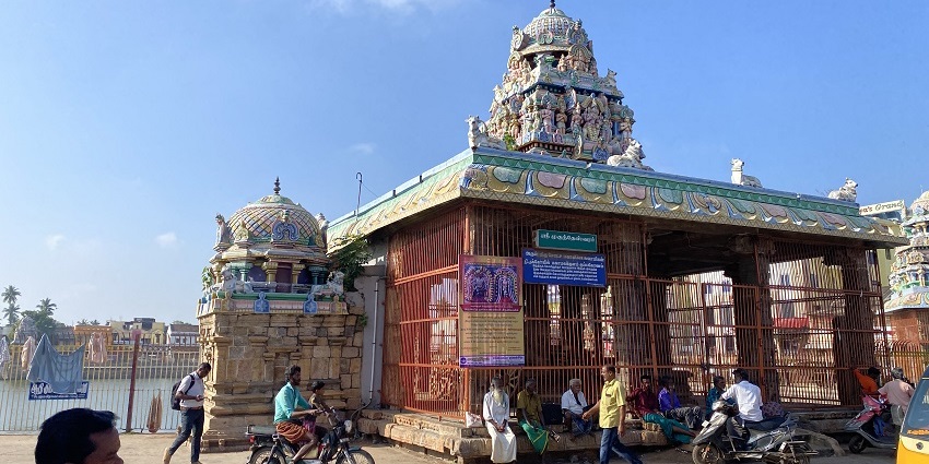 Kasi Viswanathar Temple entrance with intricate carvings, people, and vehicles in front.
